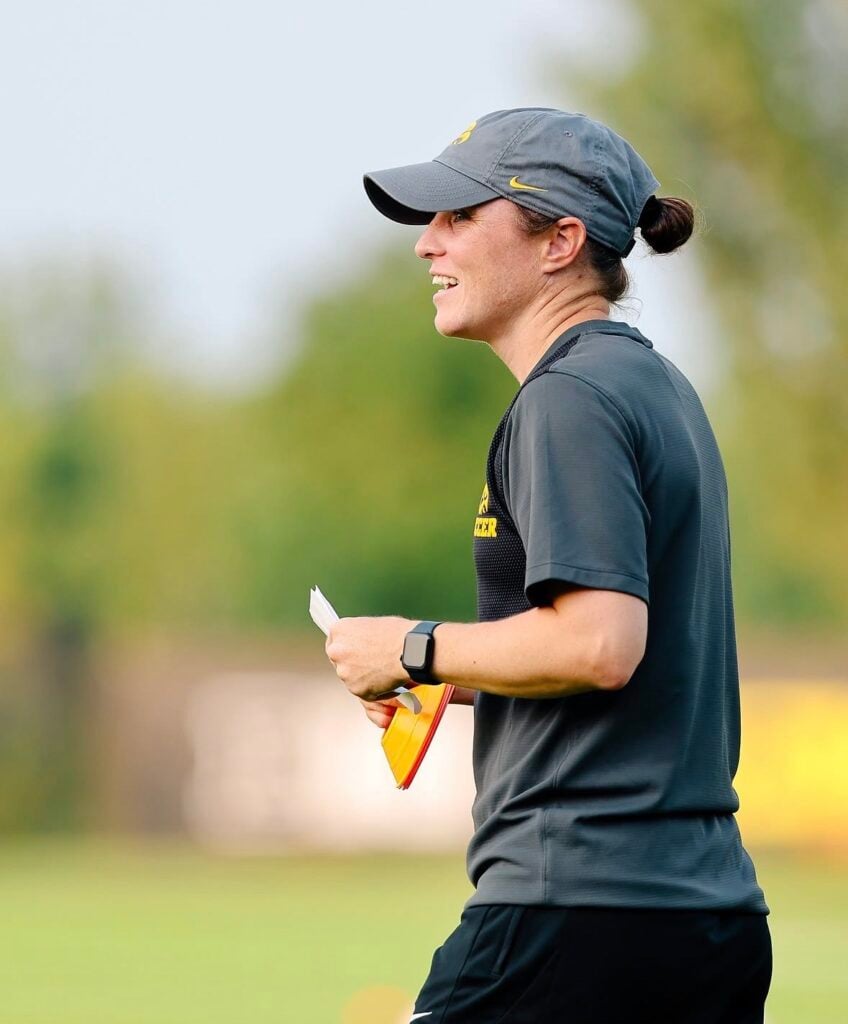 College soccer coach in a cap coaching on the field in warm evening light