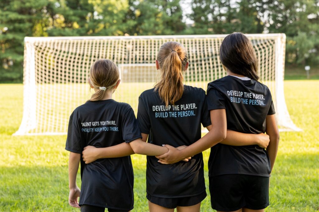 Three Whole Player teammates arm in arm facing the goal